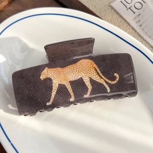 Détail d'une pince à cheveux rectangulaire motif léopard sur une assiette blanche
