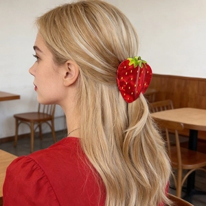 Pince à cheveux fraise mignonne en acrylique rouge montrée sur cheveux blonds