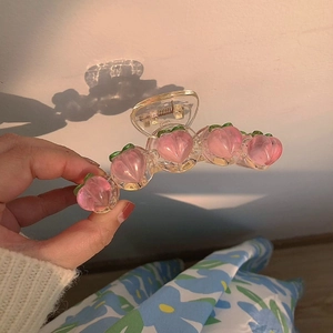 Détail d'une pince à cheveux pêche rose avec des breloques de fruits 3D en résine transparente