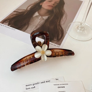 Détail d'une pince à cheveux écaille avec fleur en perle blanche et étamine dorée