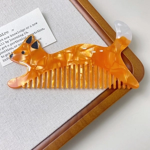 Detail of fox-shaped hair comb featuring orange marble acetate texture and wide teeth
