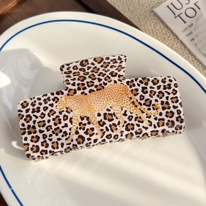 Détail de la pince à cheveux léopard avec motif guépard doré sur une assiette en céramique