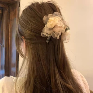 Détail d'une pince à cheveux fleur en organza champagne sur une coiffure mi-attachée