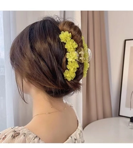 Détail d'une pince à cheveux muguet jaune tendre portée par un mannequin dans un intérieur