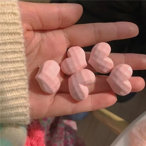 Gros plan de cinq pinces à cheveux coeur rose à facettes en résine tenues dans la main