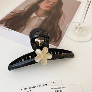 Détail de la pince à cheveux fleur noire élégante avec pétale crème et centre doré brillant