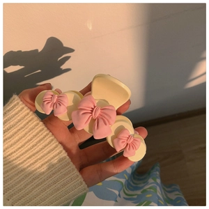 Détail d'une pince à cheveux crème ornée de trois nœuds roses décoratifs en 3D
