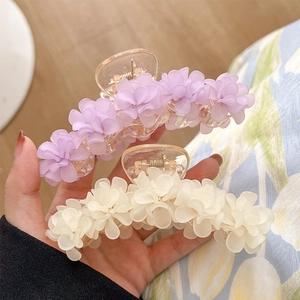 Pince à cheveux muguet avec fleurs en résine violettes et blanches vue à la main