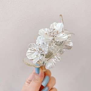Dettaglio di un fermaglio per capelli a fiore con petali bianco perla e perline di vetro