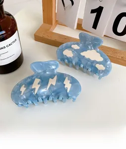 Close-up of sky blue acetate hair claws with cloud and lightning patterns on a table