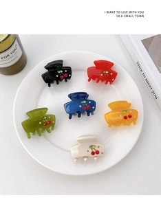 Set of 6 small acetate claw clips with red cherry designs and rhinestones in a tray