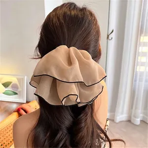 Grande elastico per capelli in chiffon champagne con bordo nero su una coda di cavallo