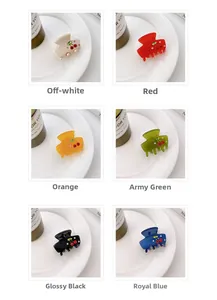 Detail of six colorful acetate cherry hair claws with rhinestones on a white porcelain dish