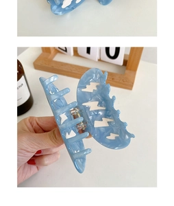 Detail view of blue marble acetate shark hair claw clip with golden metal spring