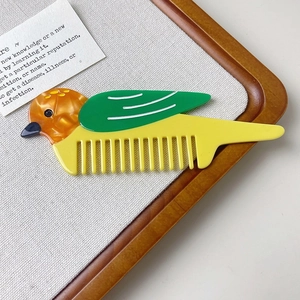 Close-up of bird-shaped acetate hair comb with smooth yellow, green and amber textures