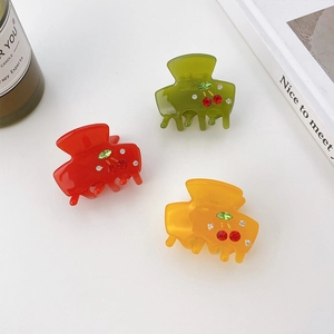 Three acetate hair claws with rhinestone cherry designs in red, olive green and amber yellow