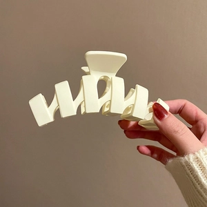 Large matte cream geometric shark hair claw clip held in hand for elegant updos