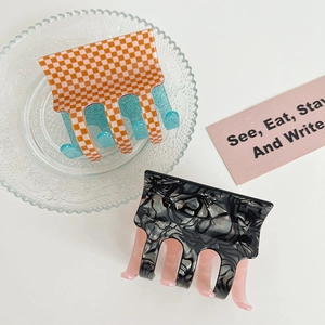 Detail view of acetate square hair claws in checkerboard and marble patterns on a glass plate