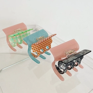Three acetate square hair claws with checkered and marble patterns on display stands