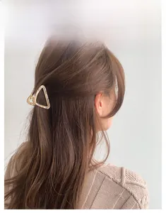 Detail of a triangle marble acetate hair claw with a gold alloy frame on model's hair
