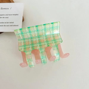 Detail of green and yellow checkered acetate hair claw clip with soft pink inner teeth