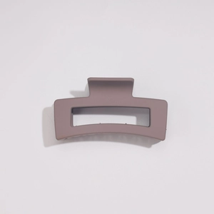 Gros plan sur une grande pince à cheveux rectangulaire gris-mauve mat au design creux