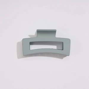 Détail macro d'une grande pince à cheveux rectangulaire mate gris-vert pour la coiffure
