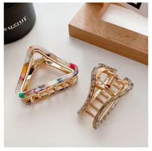 Detail view of acetate claw clips with floral patterns and gold alloy frames for hair styling