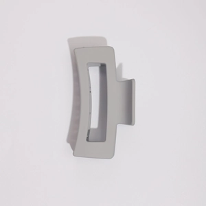 Gros plan d'une pince à cheveux rectangulaire gris mat minimaliste pour coiffure élégante