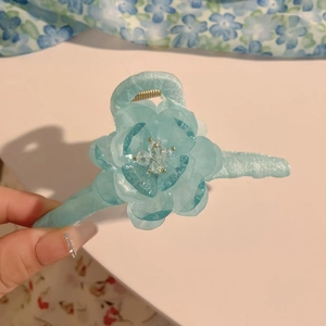 Details einer hellblauen Blumen-Haarklammer mit Kristallperlen und Plüschgriff-Textur