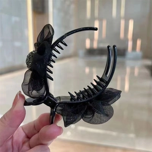 Detail of a large black shark hair claw with organza bow and sparkling rhinestones