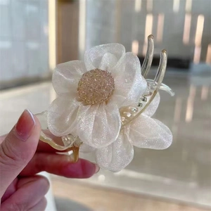Detail of camellia hair claw clip with delicate organza petals and gold center