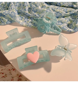 Makroaufnahme matter blauer Haarklammern mit Blumen-, Schmetterlings- und Herzmotiven