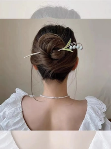 Elegante lelie van dalen haarspeld gedragen in een knot met witte bloemen en groene accenten