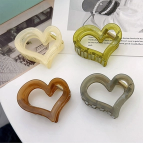 Set of four heart-shaped hair claws in cream, grey, green, and amber translucent resin