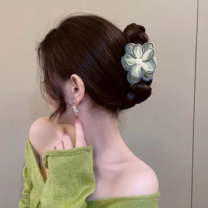 Detail of light green mesh camellia hair claw with delicate pearl stamen and layers