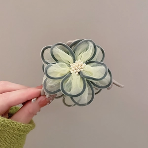 Detail of camellia hair claw featuring light yellow mesh petals and pearl stamens