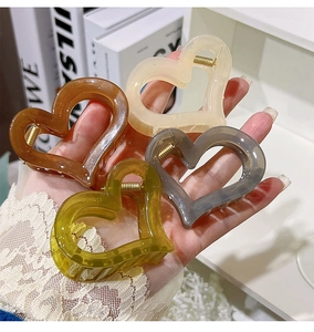 Detail of four-color heart-shaped hollow hair claws in amber, cream, grey and olive green