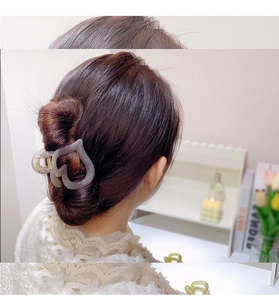 Detail shot of heart-shaped frosted hair claw clip worn on hair with a metal spring