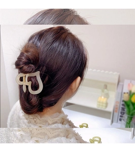 Detail showing a heart-shaped matte beige hair claw clip styled on long wavy hair