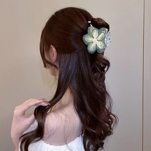 Detail showing layers of a light green camellia hair claw clip with pearl center
