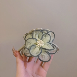 Detail of camellia hair claw clip with grey-green mesh petals and pearl center