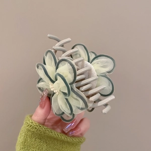 Detail of light green mesh camellia hair claw with pearl center and green edging