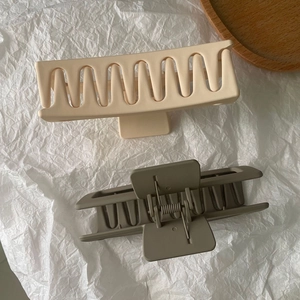 Detail view of large matte rectangle hair claws in cream white and morandi grey-green colors