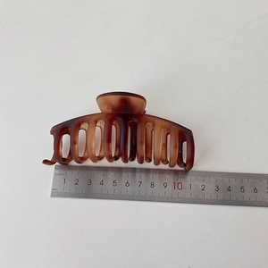 Detail view of a 11cm matte tortoiseshell hair claw clip measured with a metal ruler