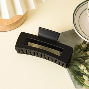 Close-up of matte black rectangular hair claw clip for thick hair with sleek hollow design