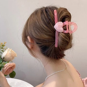 Dettaglio della molletta a cuore in marmo rosa che tiene i capelli in una acconciatura chic