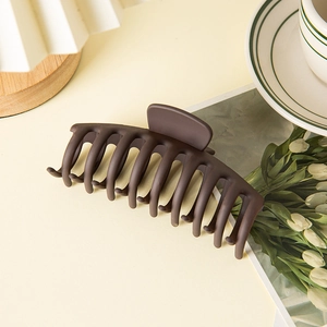 Macro shot of large dark brown matte shark clip for hair buns against aesthetic decor