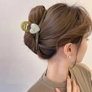 Elegante pinza per capelli cuore verde oliva mostrata in un'acconciatura su una modella