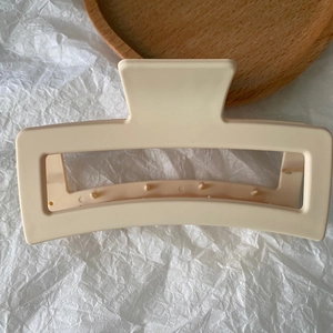 Detail view of a 13cm matte beige rectangular claw clip on a minimalist wooden tray